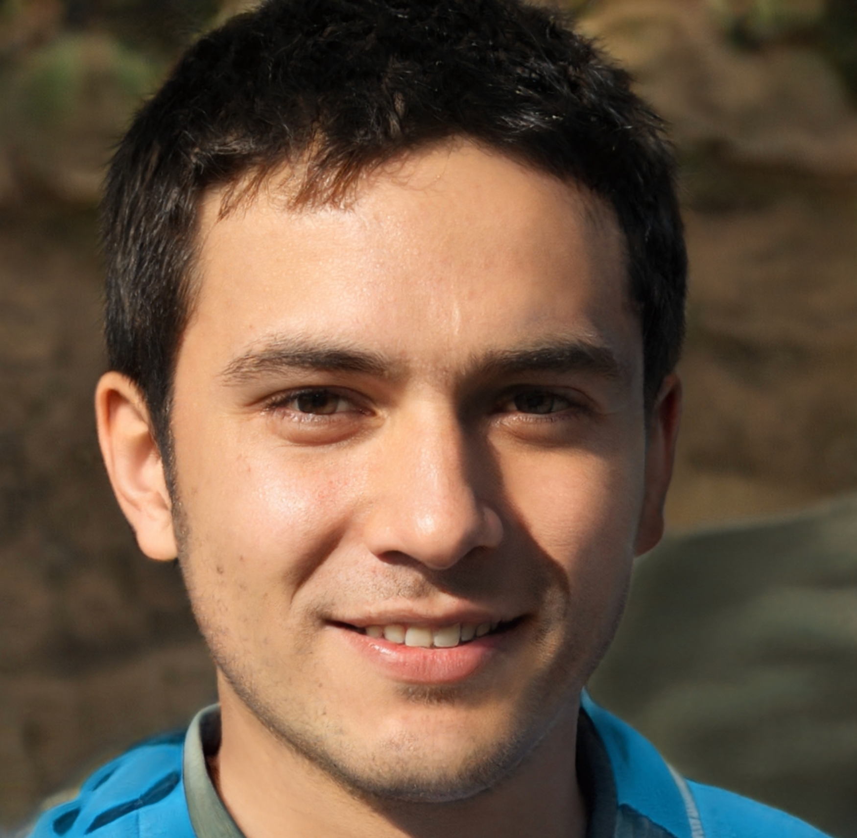 Man smiling, brown eyes, dark hair, wearing a blue jacket, outdoors.