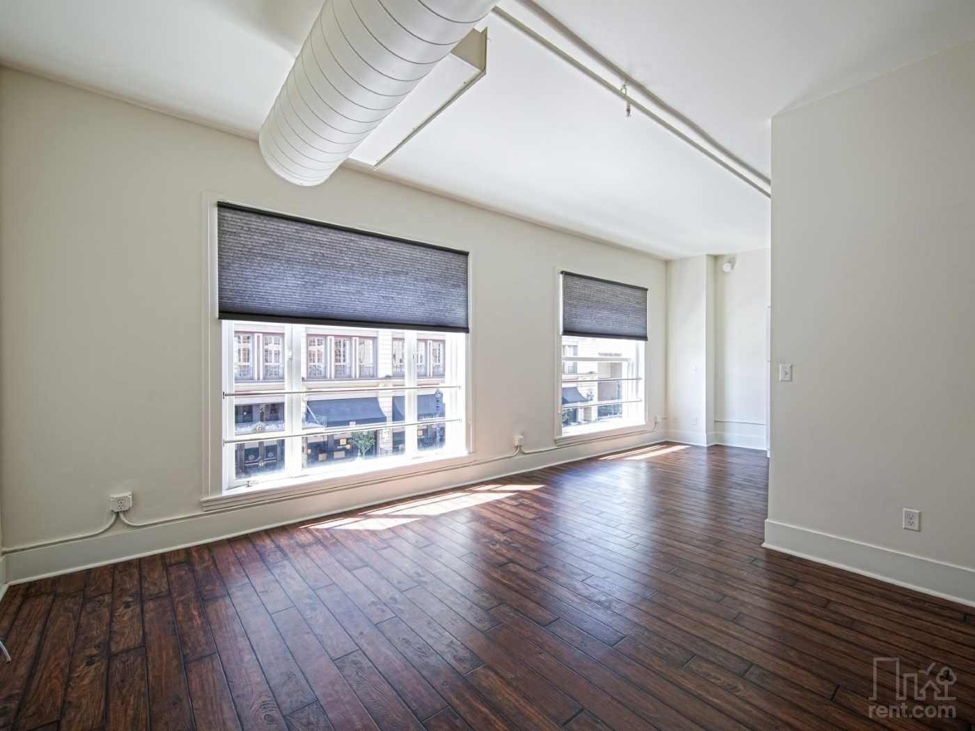 A large empty room with hardwood floors and white walls.