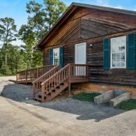 Wooden cabin with front porch and steps in a wooded area