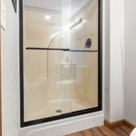 Glass shower enclosure with black frame in a beige bathroom corner