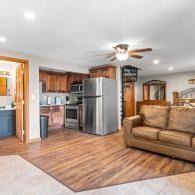 Open-concept kitchen and living room with stainless steel appliances, brown sofa, and wood flooring