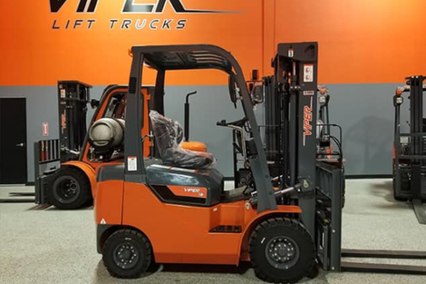 A forklift is parked in front of a wall that says lift trucks.