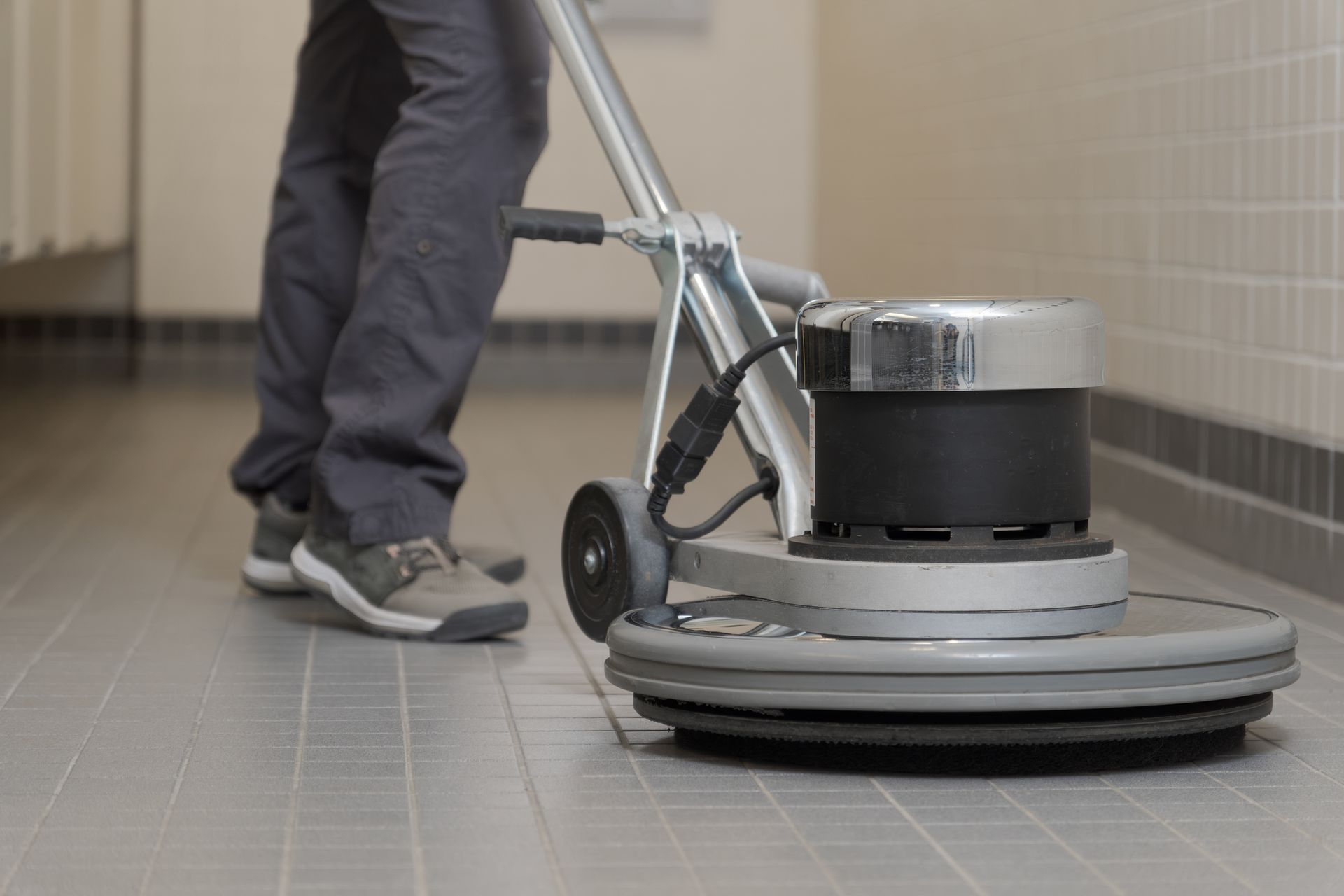 A person is using a machine to clean a tiled floor.