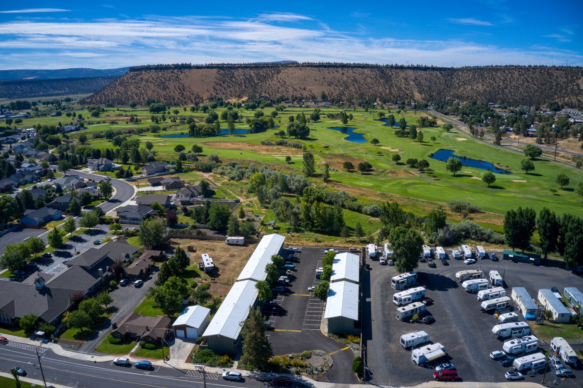 An aerial view of a residential area with a golf course in the background.