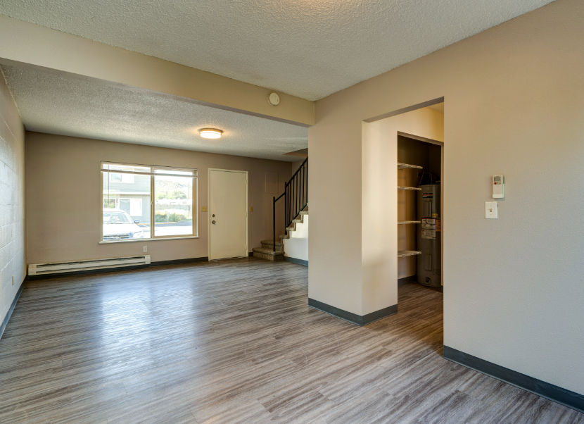 An empty living room with hardwood floors and a staircase.