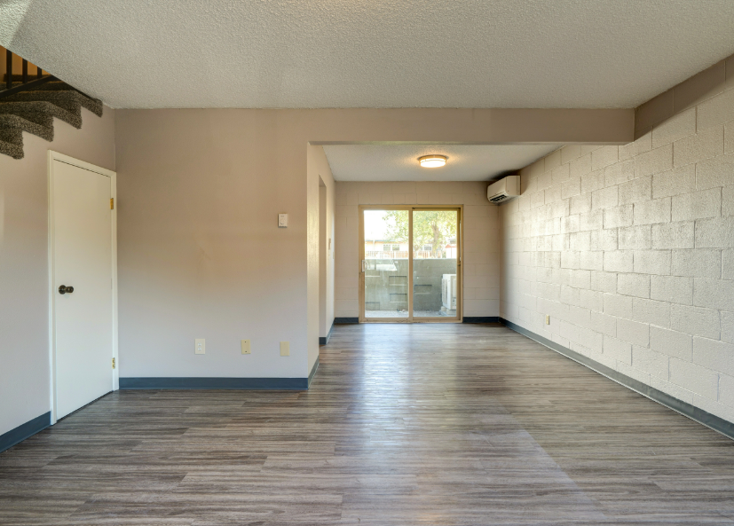 An empty living room with hardwood floors and a sliding glass door.