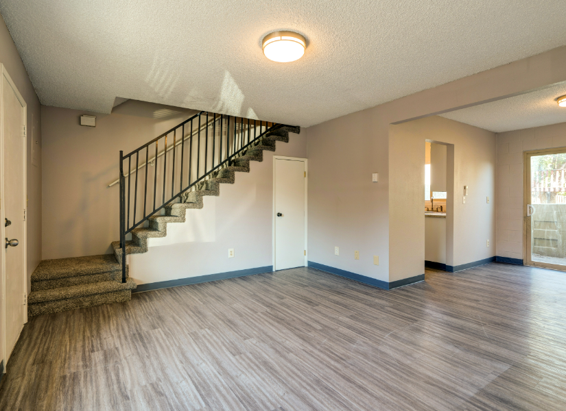 An empty living room with hardwood floors and sliding glass doors.