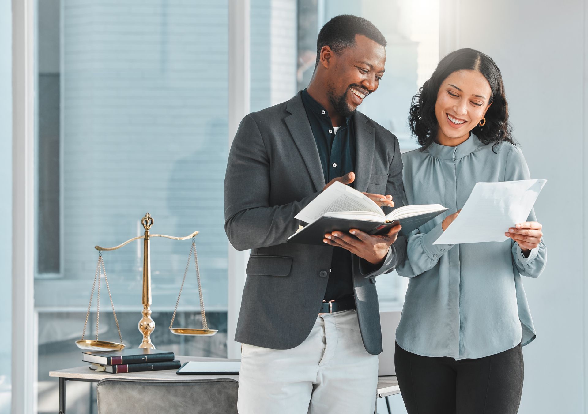 A man and a woman are standing next to each other in an office looking at papers.