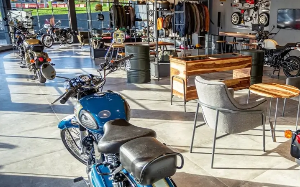Blue motorcycle parked outside a sunlit café with tables and chairs