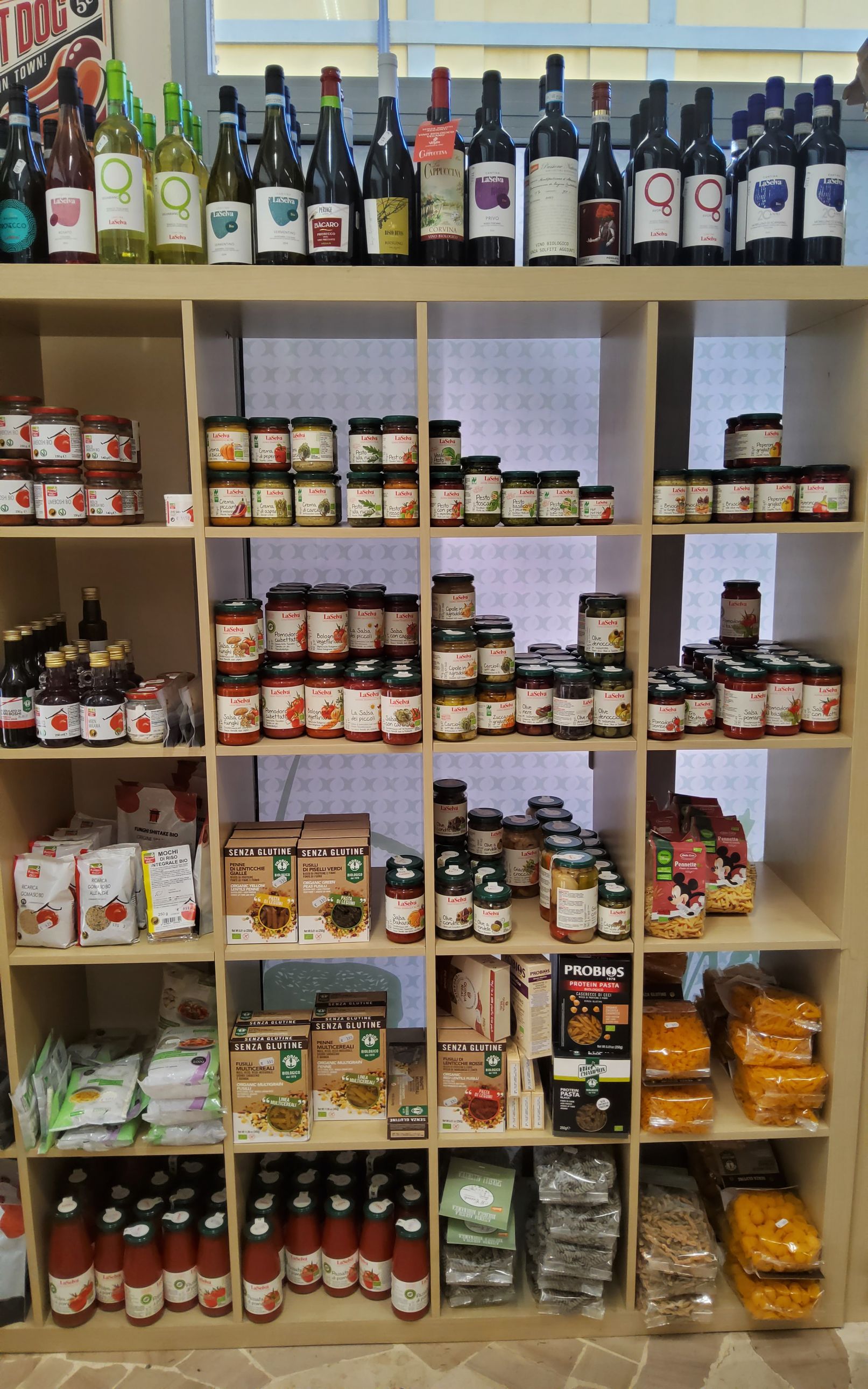 Uno scaffale di un negozio pieno di cibo e bottiglie di vino.