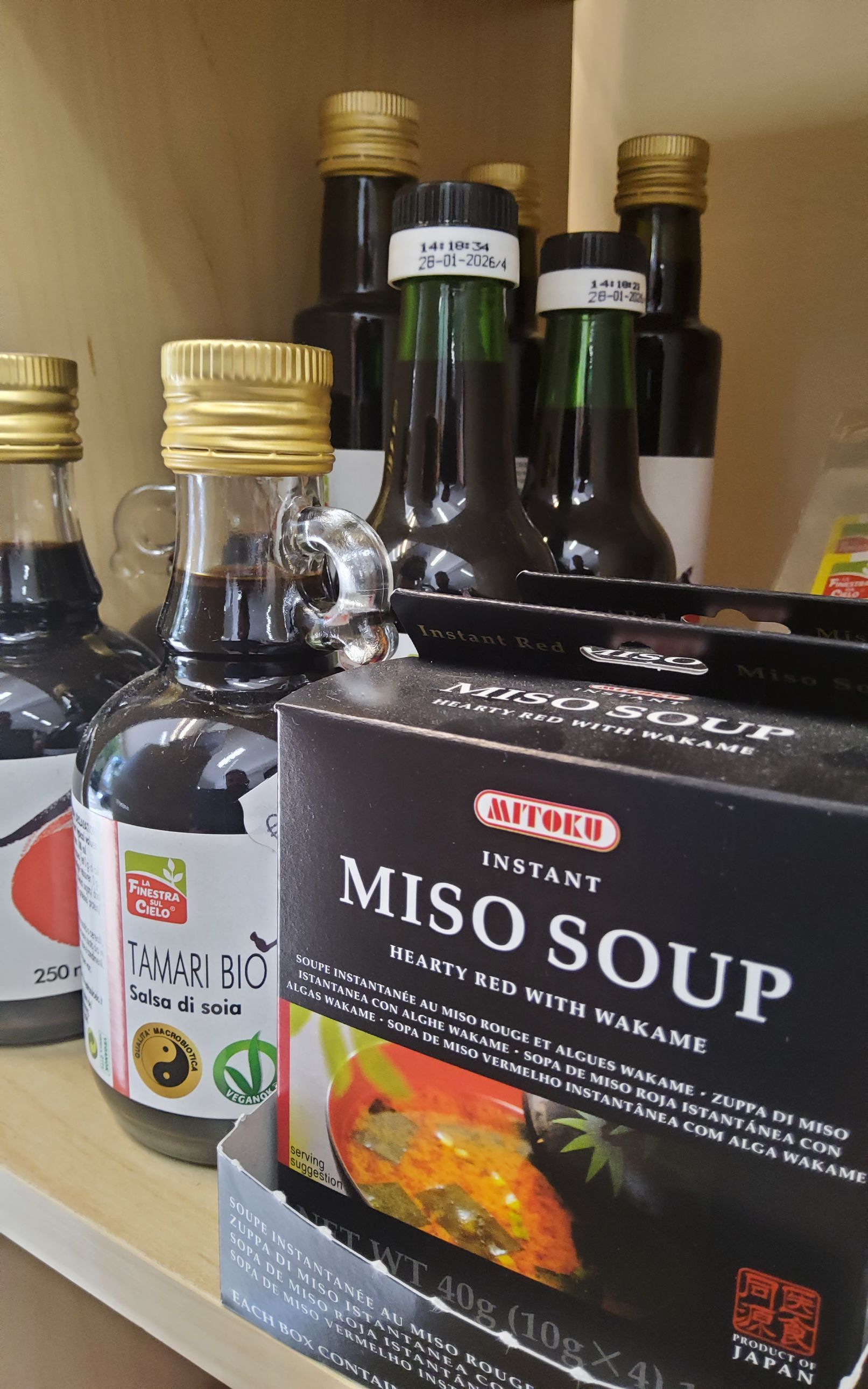 Una scatola di zuppa di miso è appoggiata su uno scaffale accanto a bottiglie di zuppa di miso.