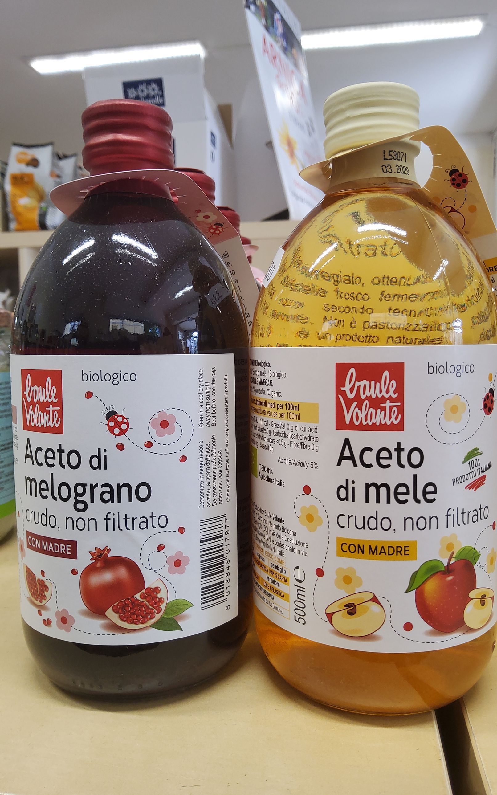 Due bottiglie di aceto di mele sono appoggiate una accanto all'altra su un tavolo.