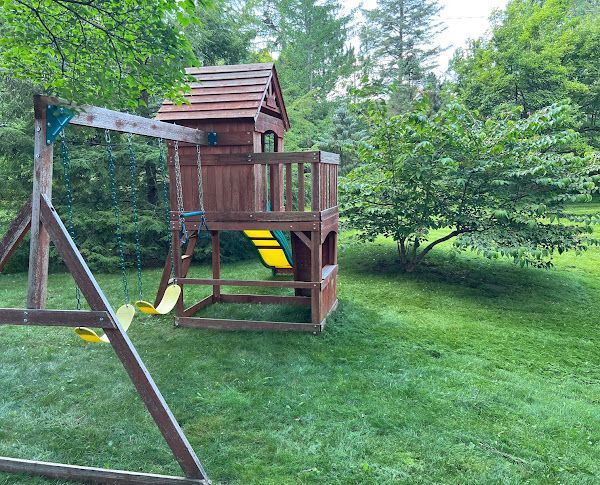 A wooden playground set is sitting on top of a lush green lawn.