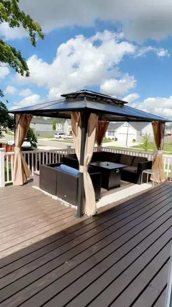 A gazebo with a couch and a table on a deck.