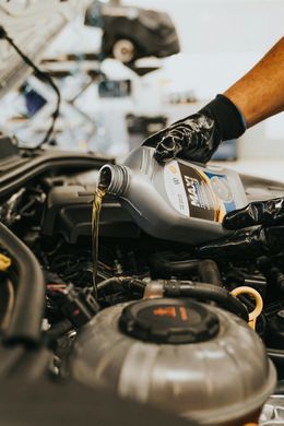 A person is pouring oil into a car engine.