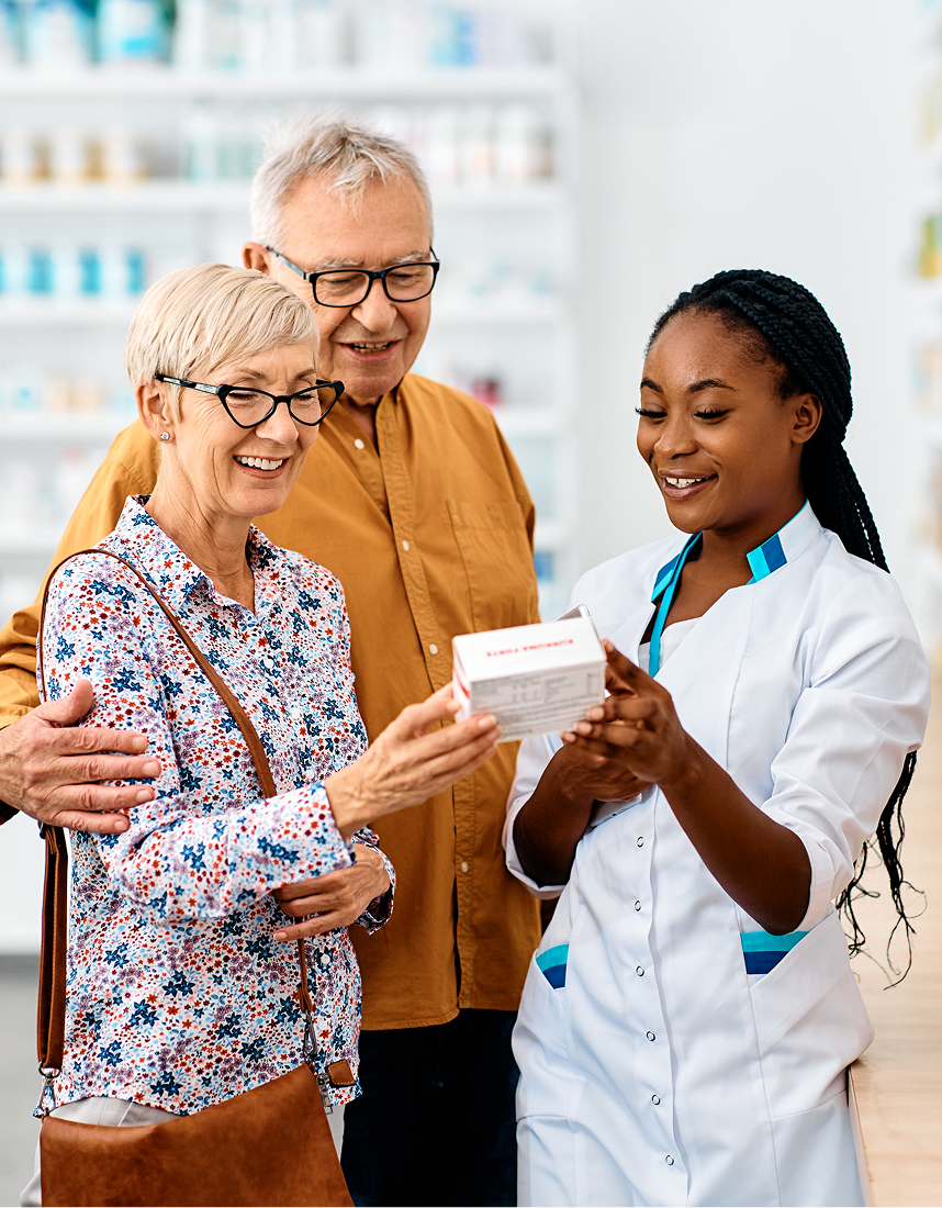 An elderly couple is looking at a box of pills in a pharmacy.