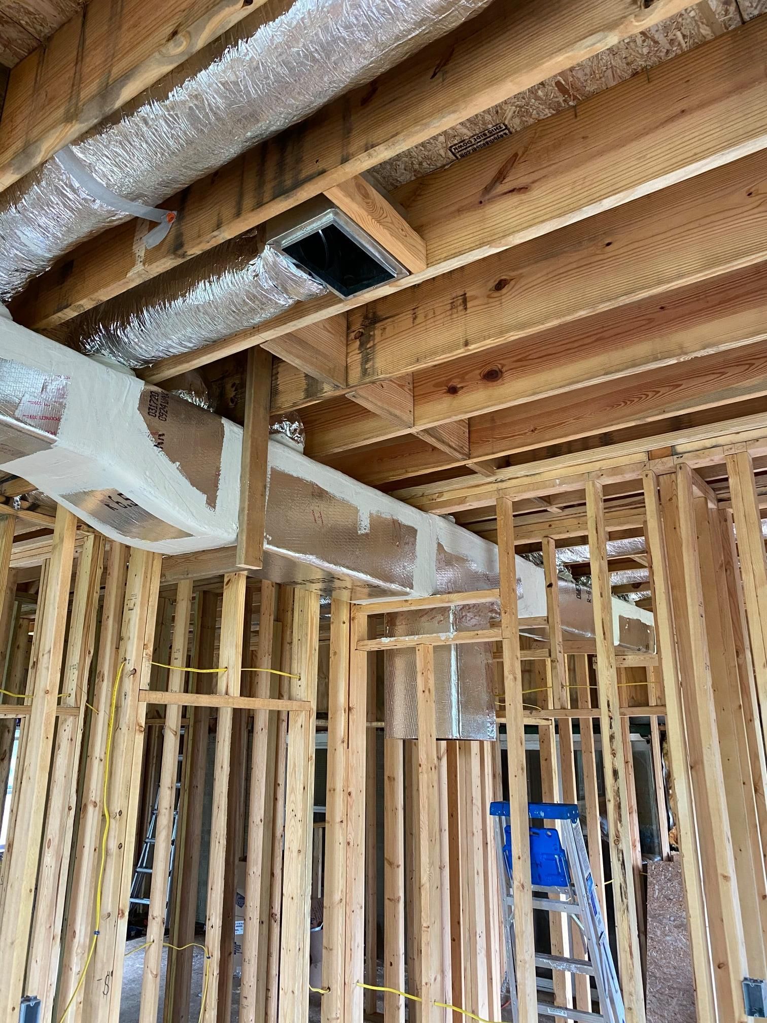 A house is being built with wooden beams and a ladder.
