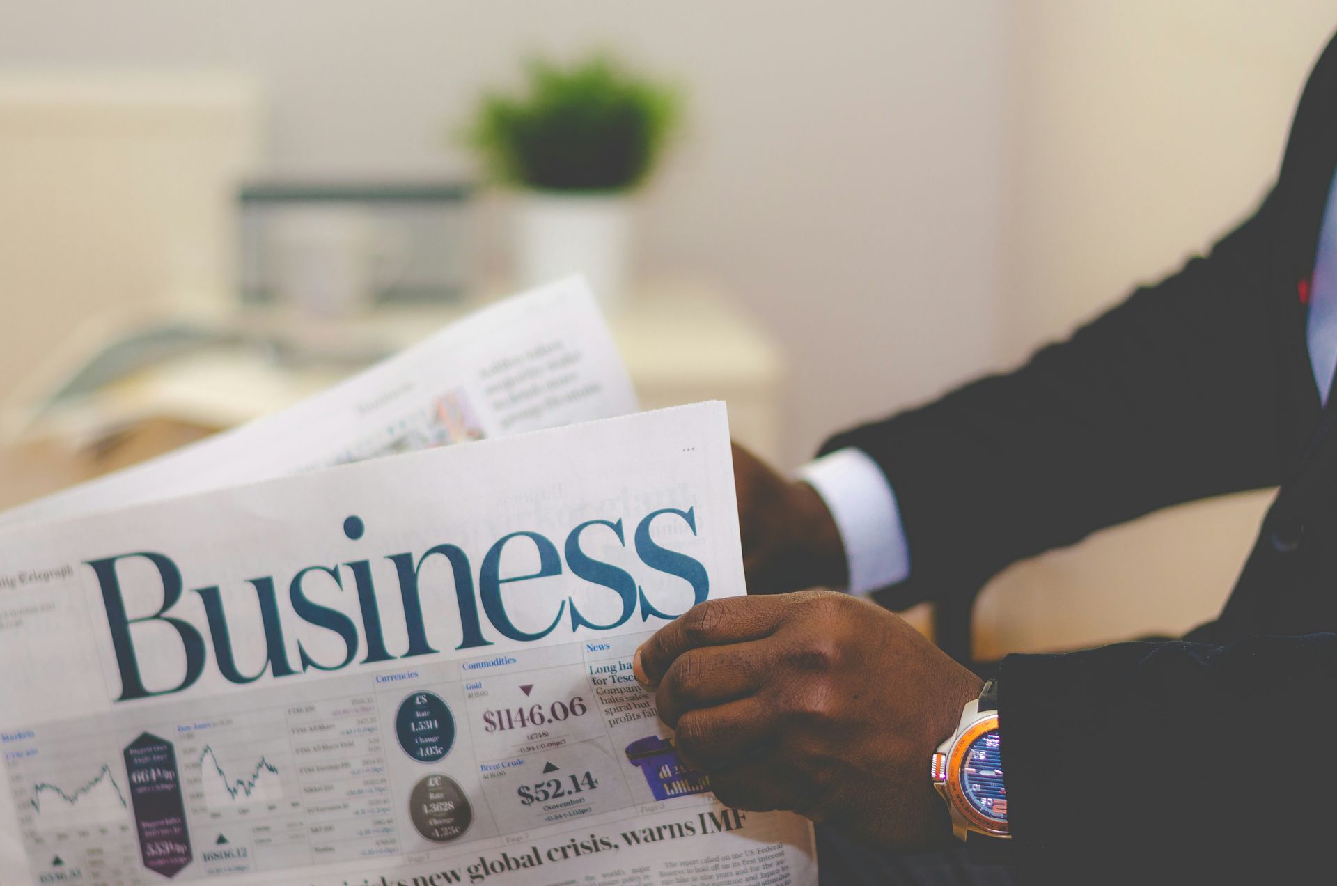 A man in a suit is reading a business newspaper