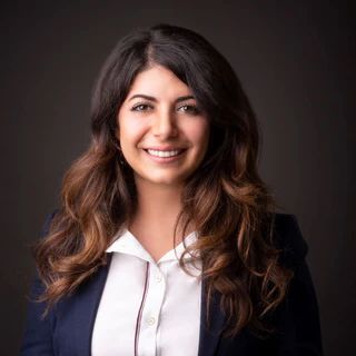 A woman in a blue jacket and white shirt is smiling for the camera.