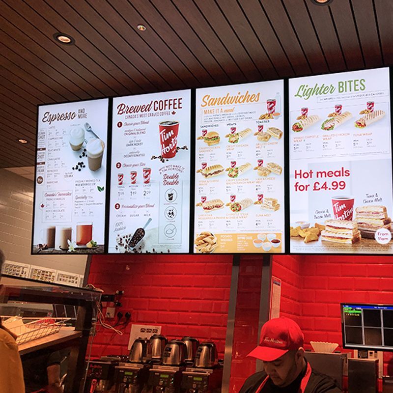 A man in a red hat is standing in front of a menu that says hot meals for 4.99