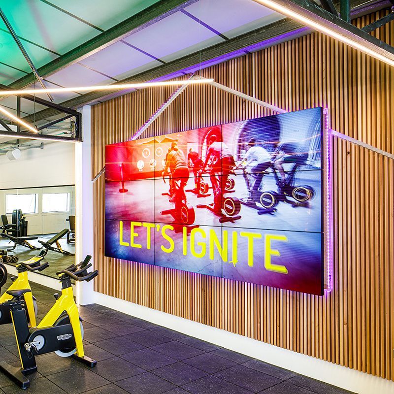 A gym with a large screen on the wall that says let 's ignite