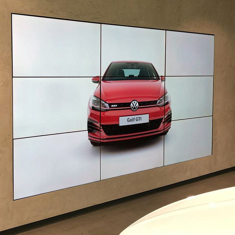 A large screen displays a picture of a red volkswagen golf on a wall.