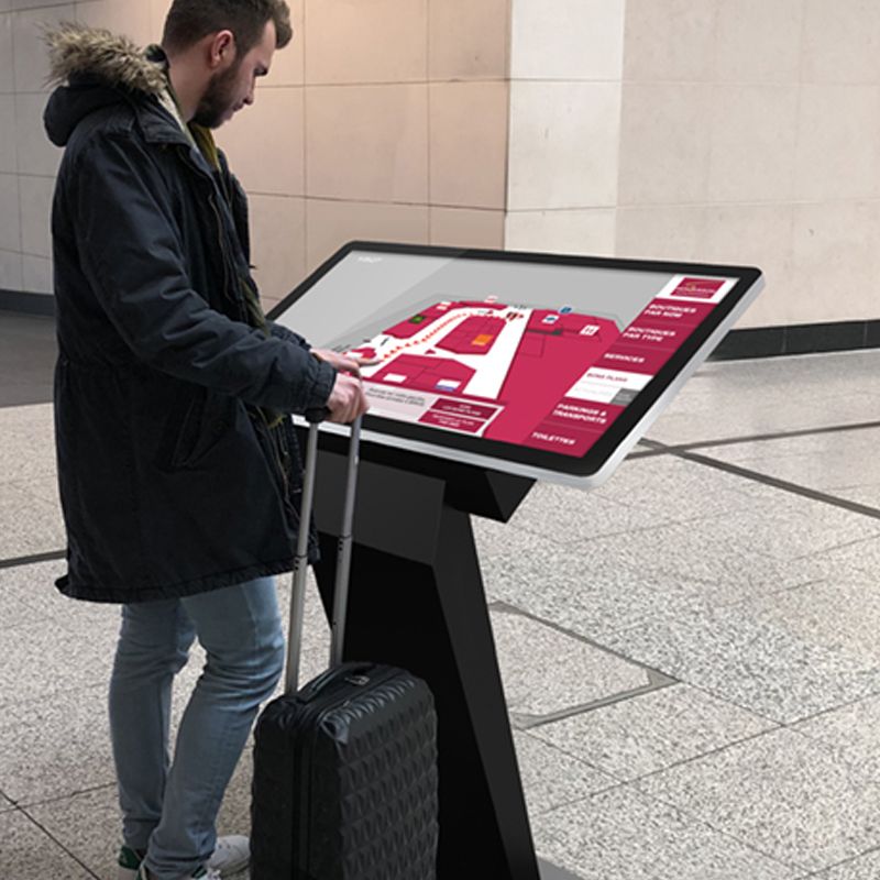 A man with a suitcase is looking at a map on a screen