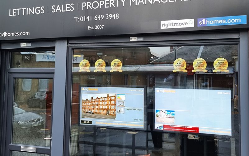 Real estate office front with window displays, awards, and the Rightmove logo.