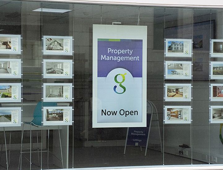 A sign in a window that says property management now open