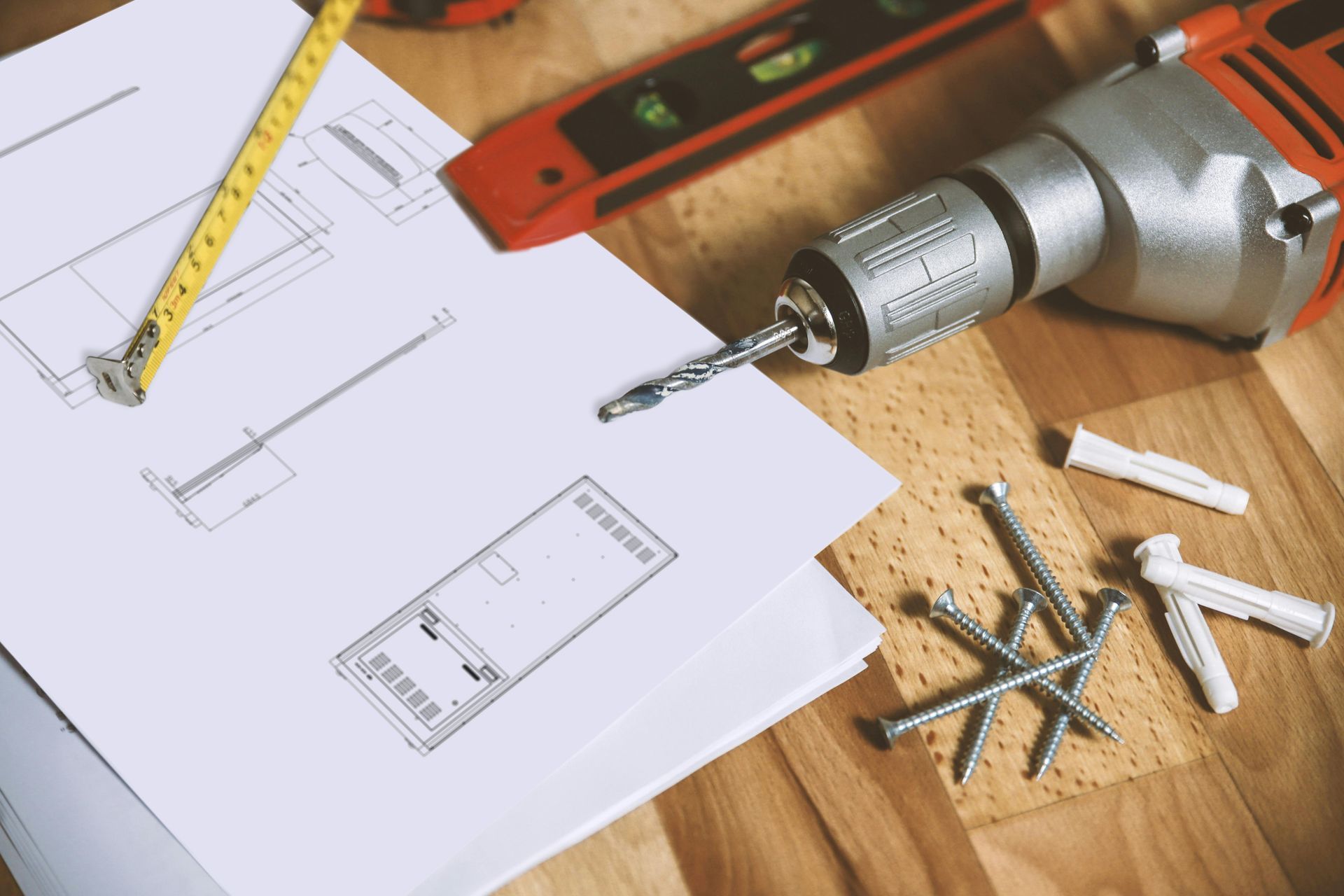 A drill is sitting on top of a piece of paper on a wooden table.