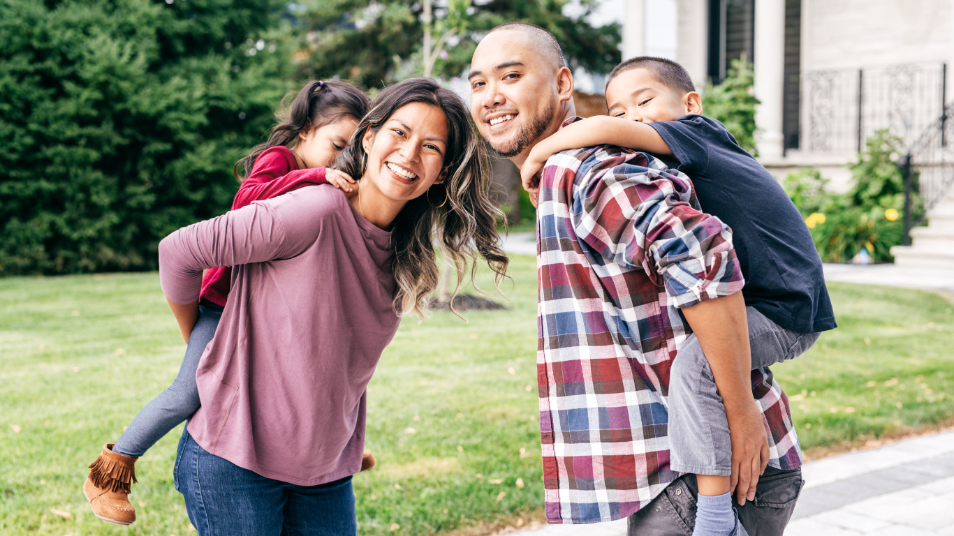 A family sits on a couch smiling during a counseling session with a professional who is taking notes.