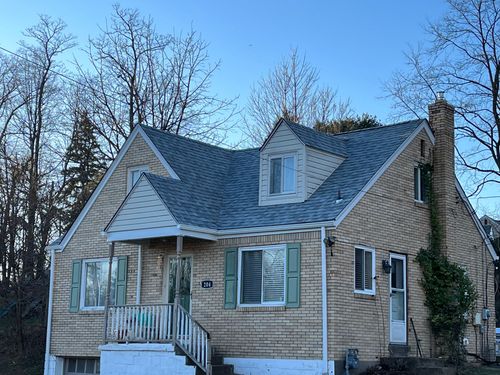 Yellow brick home with grey shingles installed on roof
