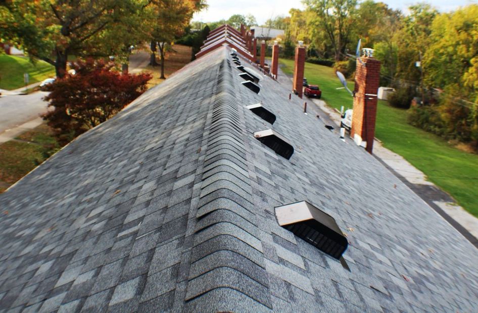 a roof from point of view from ridge, with grey shingles and black vents