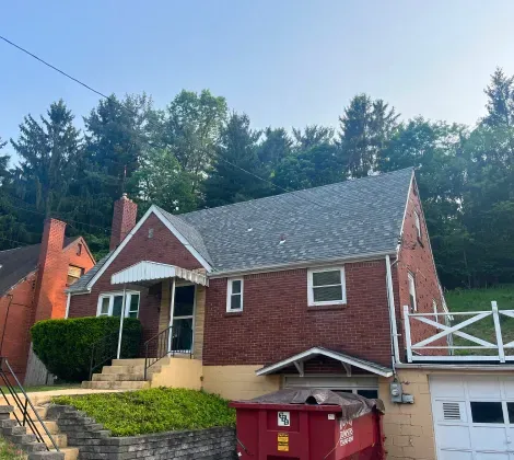 A brick house with a red dumpster in front of it.