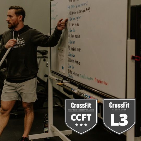 A man is standing in front of a white board that says crossfit on it