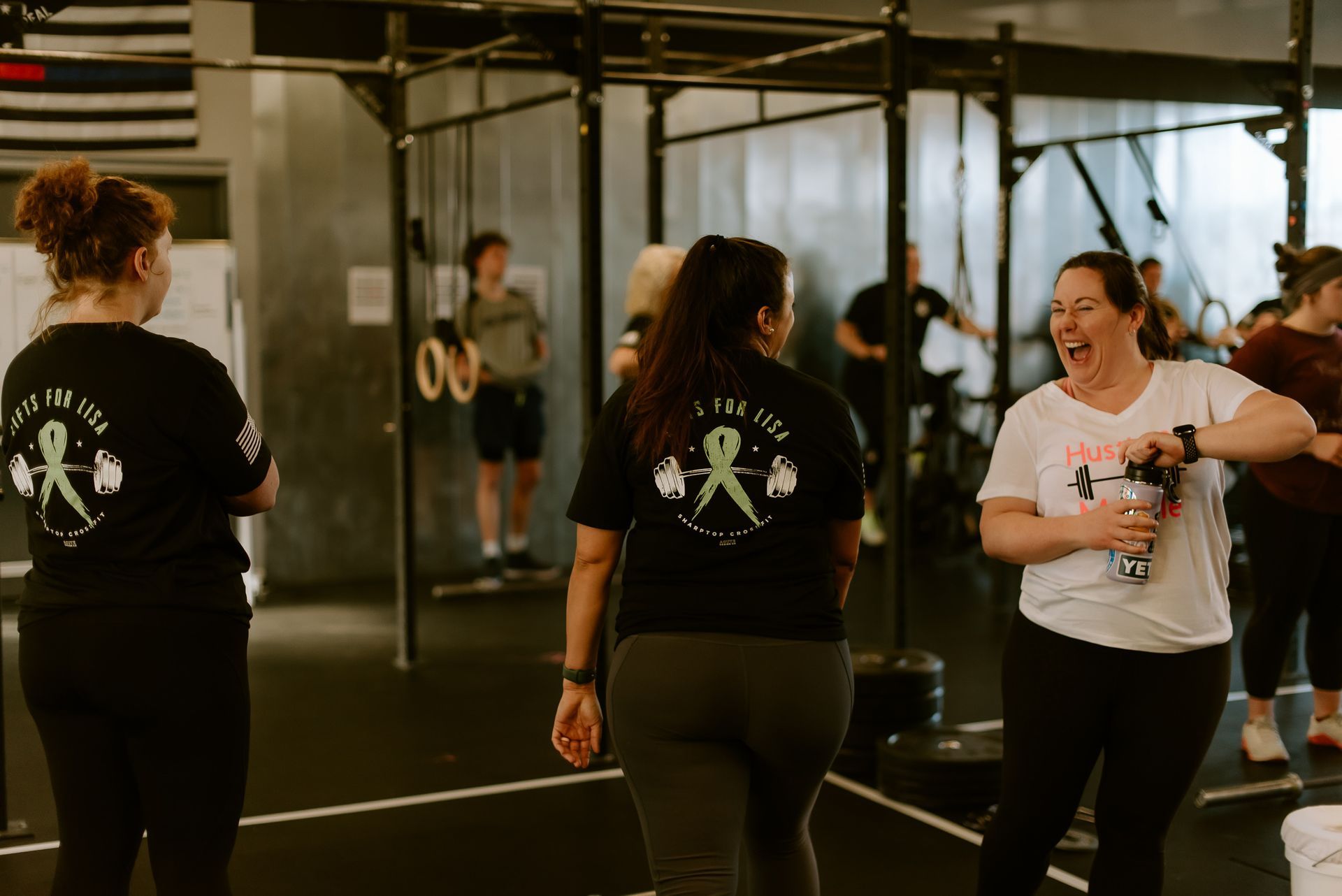 A group of women are standing in a gym talking to each other.