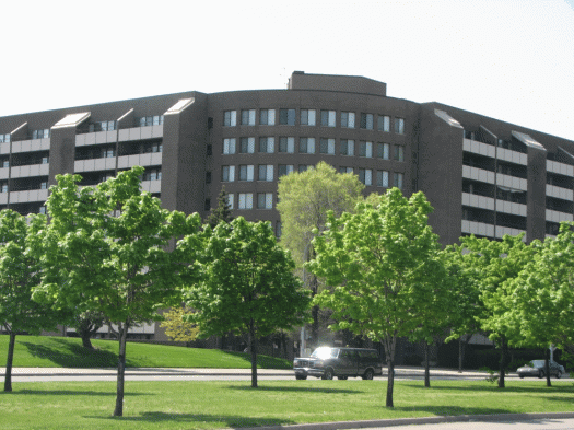 A large building with a lot of windows is surrounded by trees and grass.