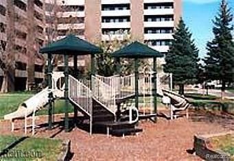 A playground with a slide and stairs in front of a building.