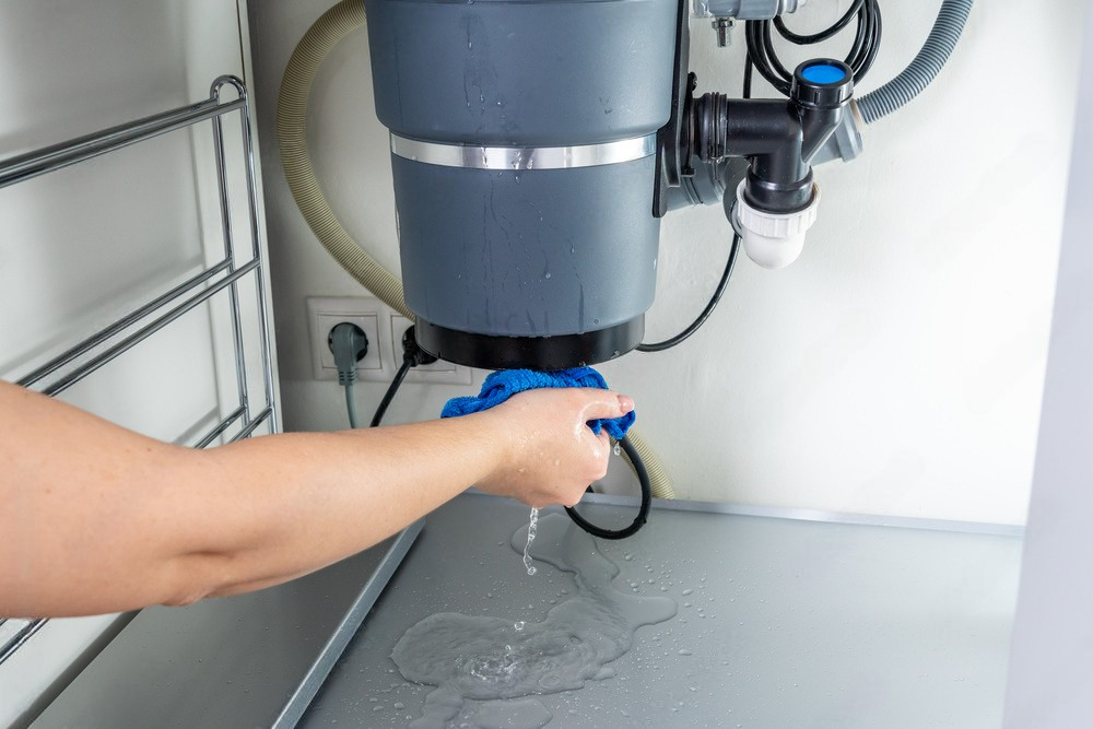 Under-sink waste leak, broken garbage chopper creates a messy cleanup scene.