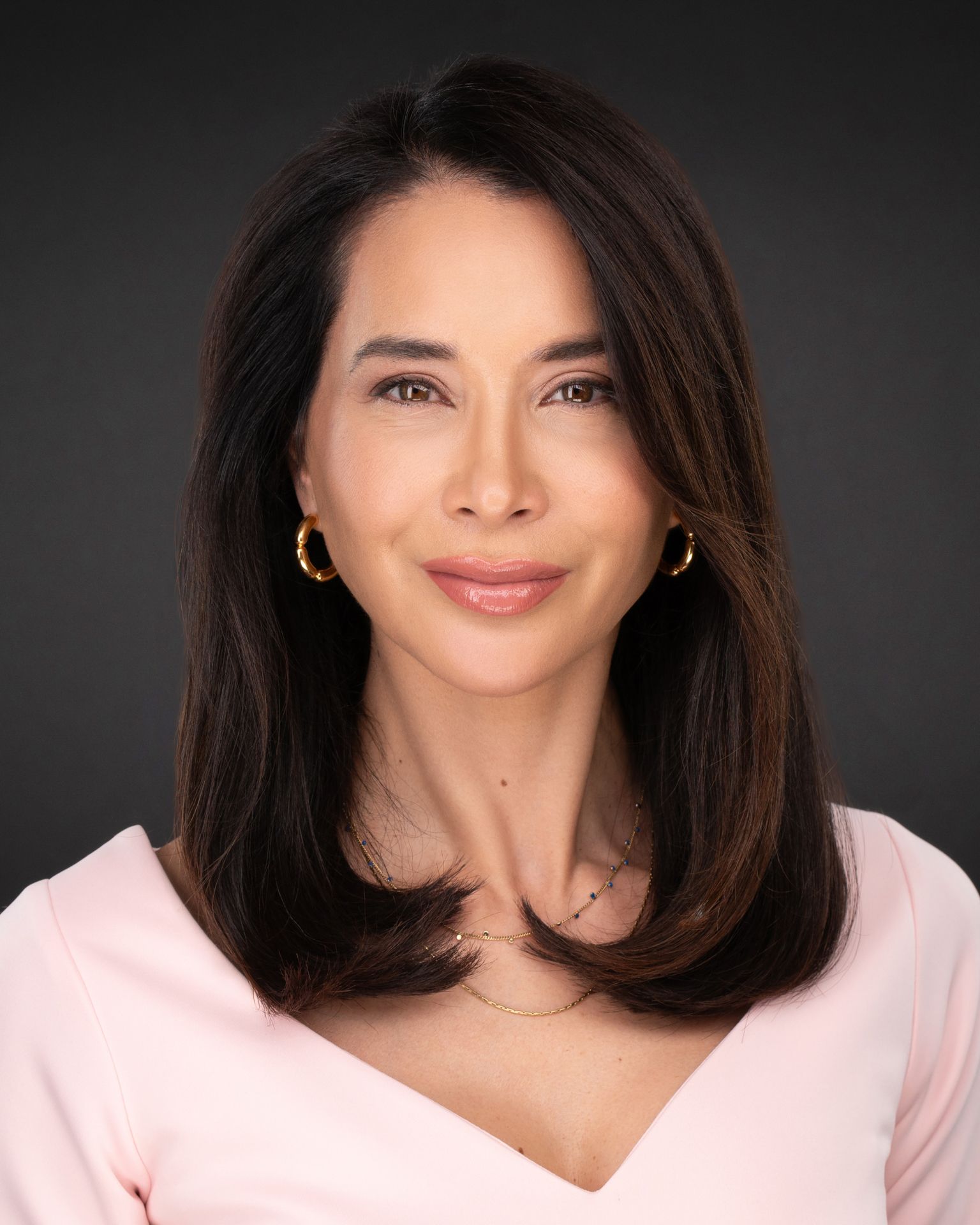 Elegant branding portrait of a female professional in a soft pink top with polished styling, captured in studio by Malena Vazquez for Art of Portraits – Miami Headshots & Portraits.