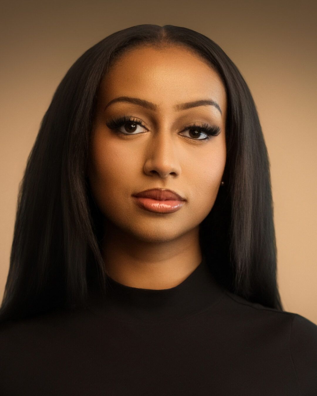 Woman with long, dark hair wearing a black turtleneck, looking directly at the viewer.