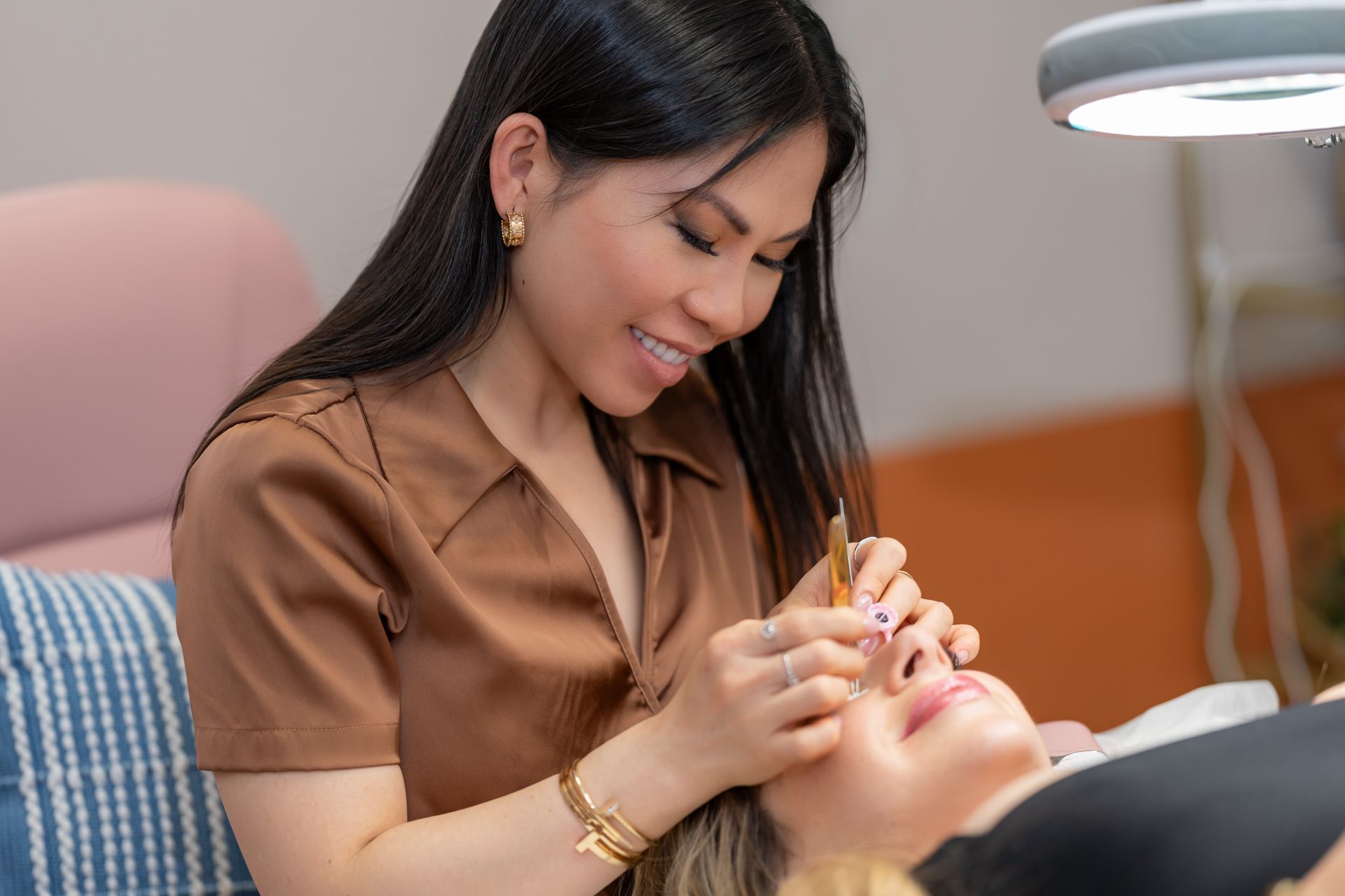 Woman applying eyelash extensions on a client in a beauty salon.