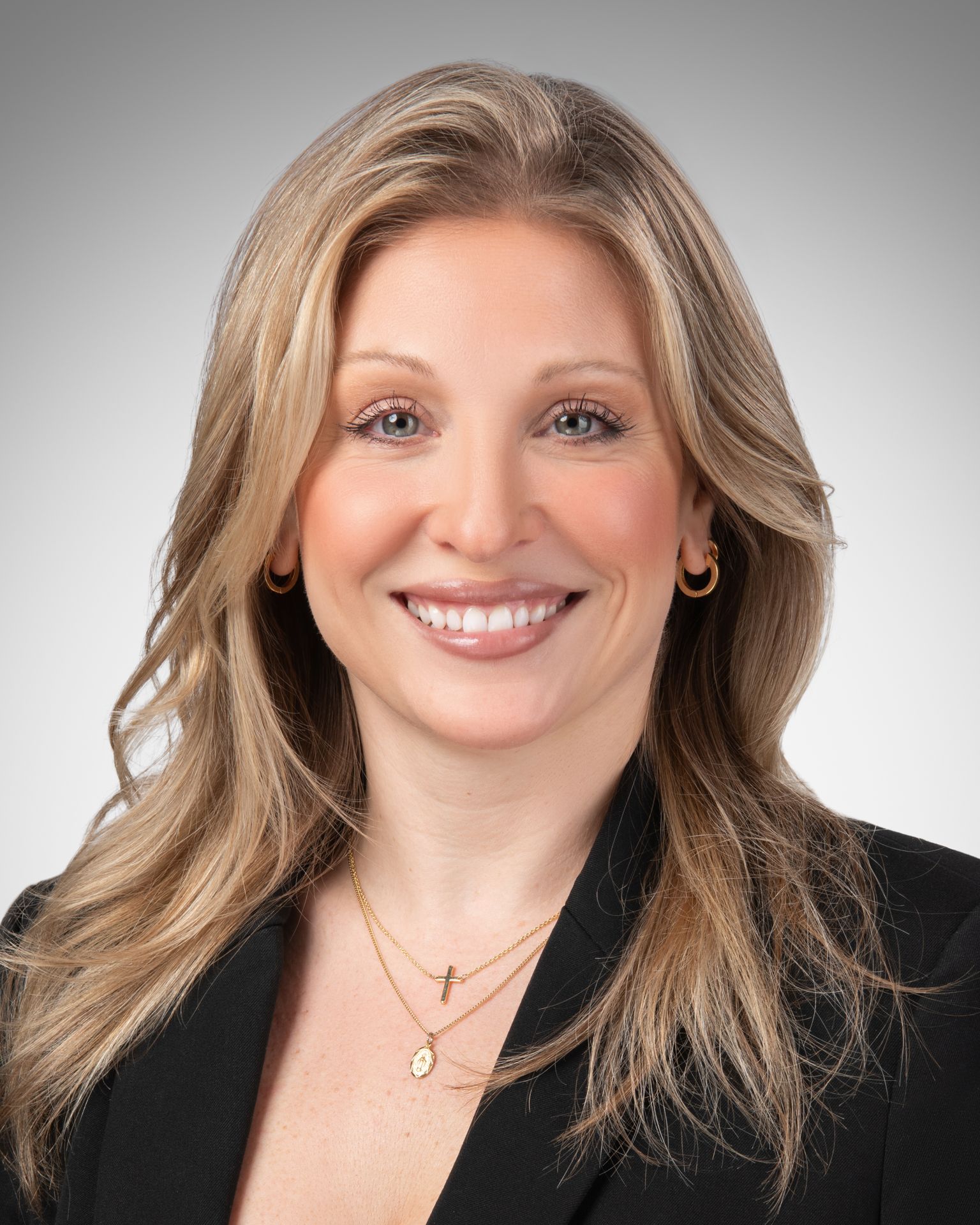 Modern professional headshot of a Philadelphia corporate professional wearing a blazer and blue shirt, studio lighting with dark backdrop.