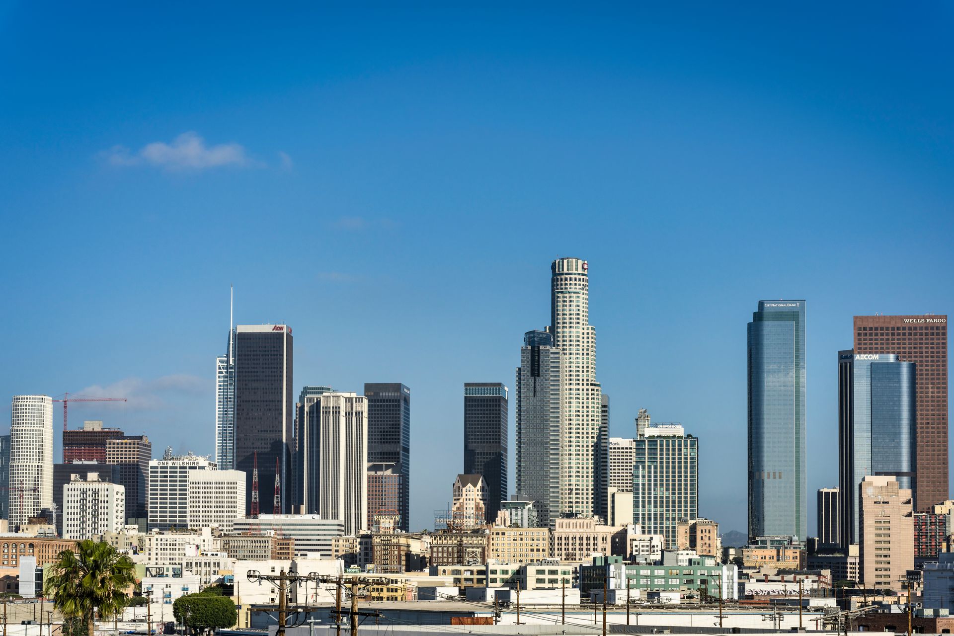 Panoramic view of downtown Los Angeles skyline with modern high-rise buildings under a clear blue sky.