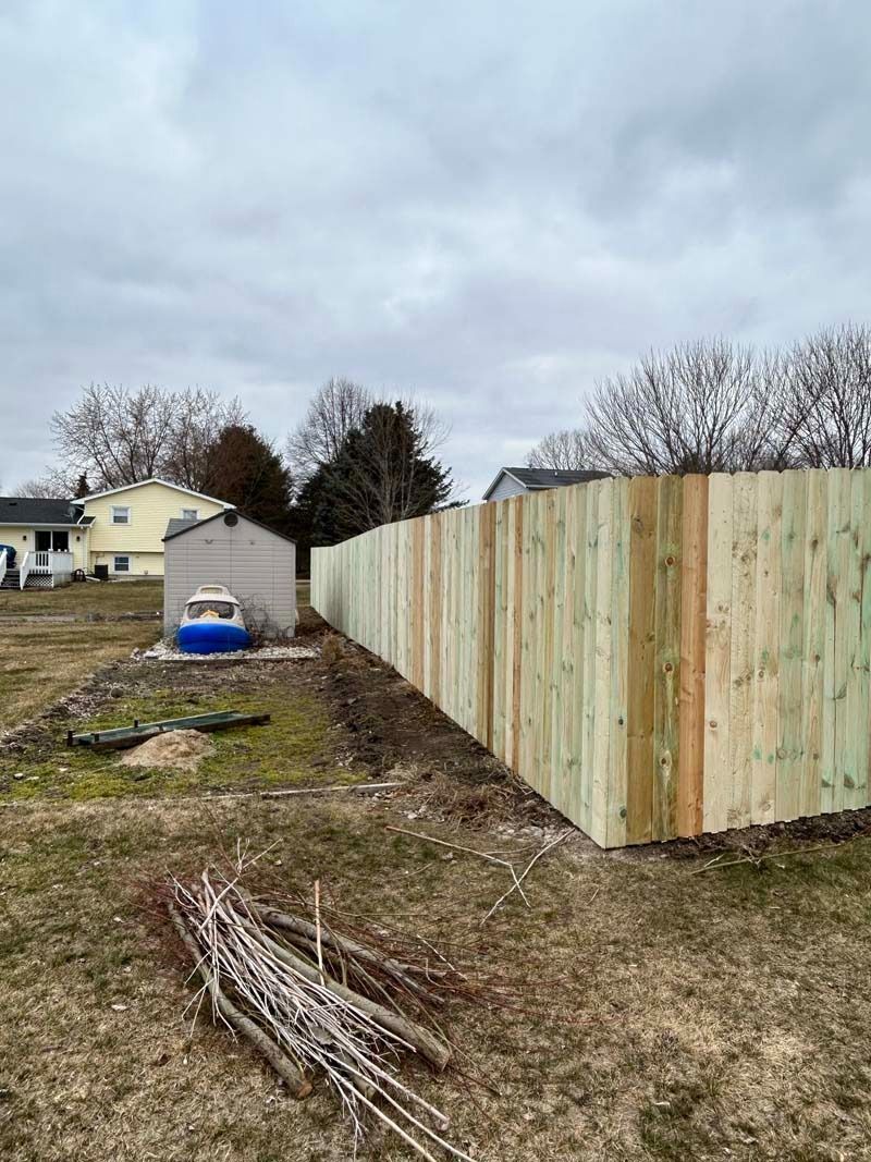 Newly constructed wooden fence in a yard, under a cloudy sky.