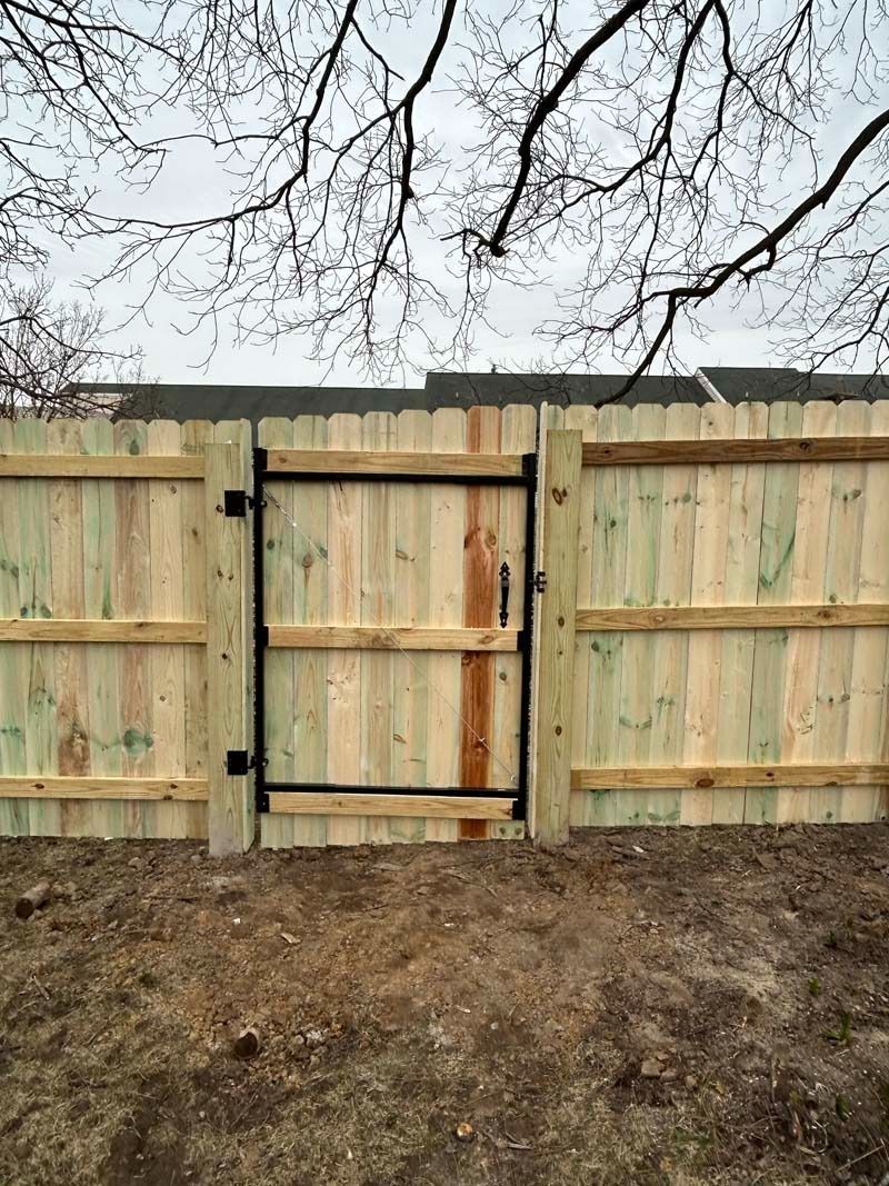 Wooden fence with black gate, light brown, outdoors.