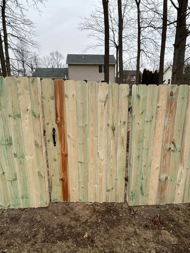 Wooden fence with a house in the background. The fence is made of vertical wooden planks.