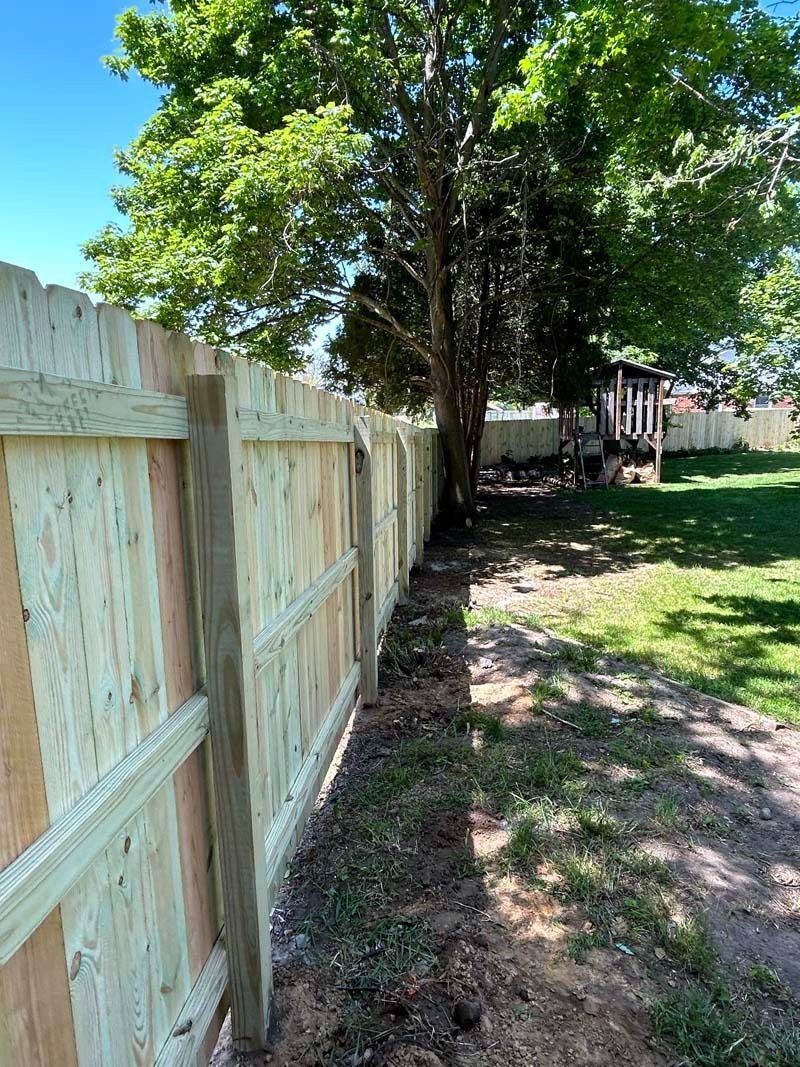 Wooden fence in a yard, with a tree beside it.