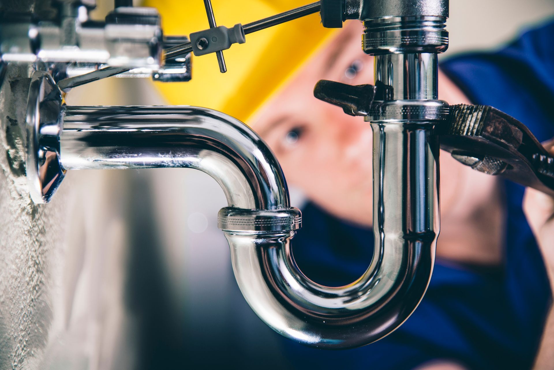 A close-up picture of a plumber is fixing a drain with an adjustable wrench A close-up picture of a plumber is fixing a drain with an adjustable wrench