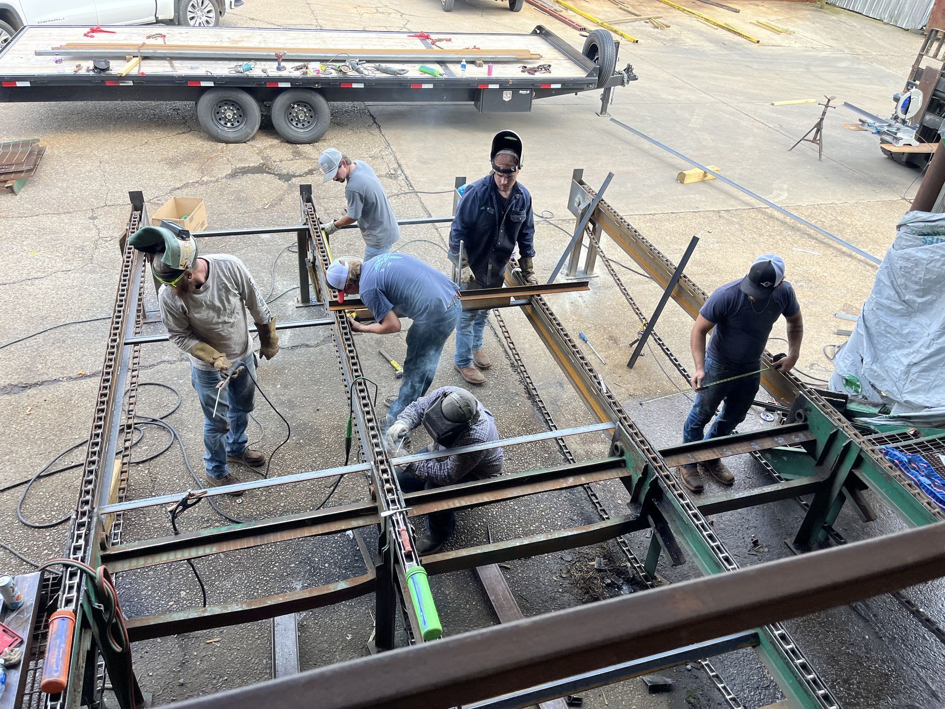 Workers welding steel beams outdoors.